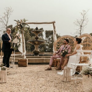 cérémonie laïque mariage, chaises squares blanches, arche en bois, officiant de cérémonie, mariés, fauteuil Emmanuelle, panier osier, gypsophile, photophore blanche, location de mobilier Béziers, location mobilier Montpellier, château Capitoul Narbonne
