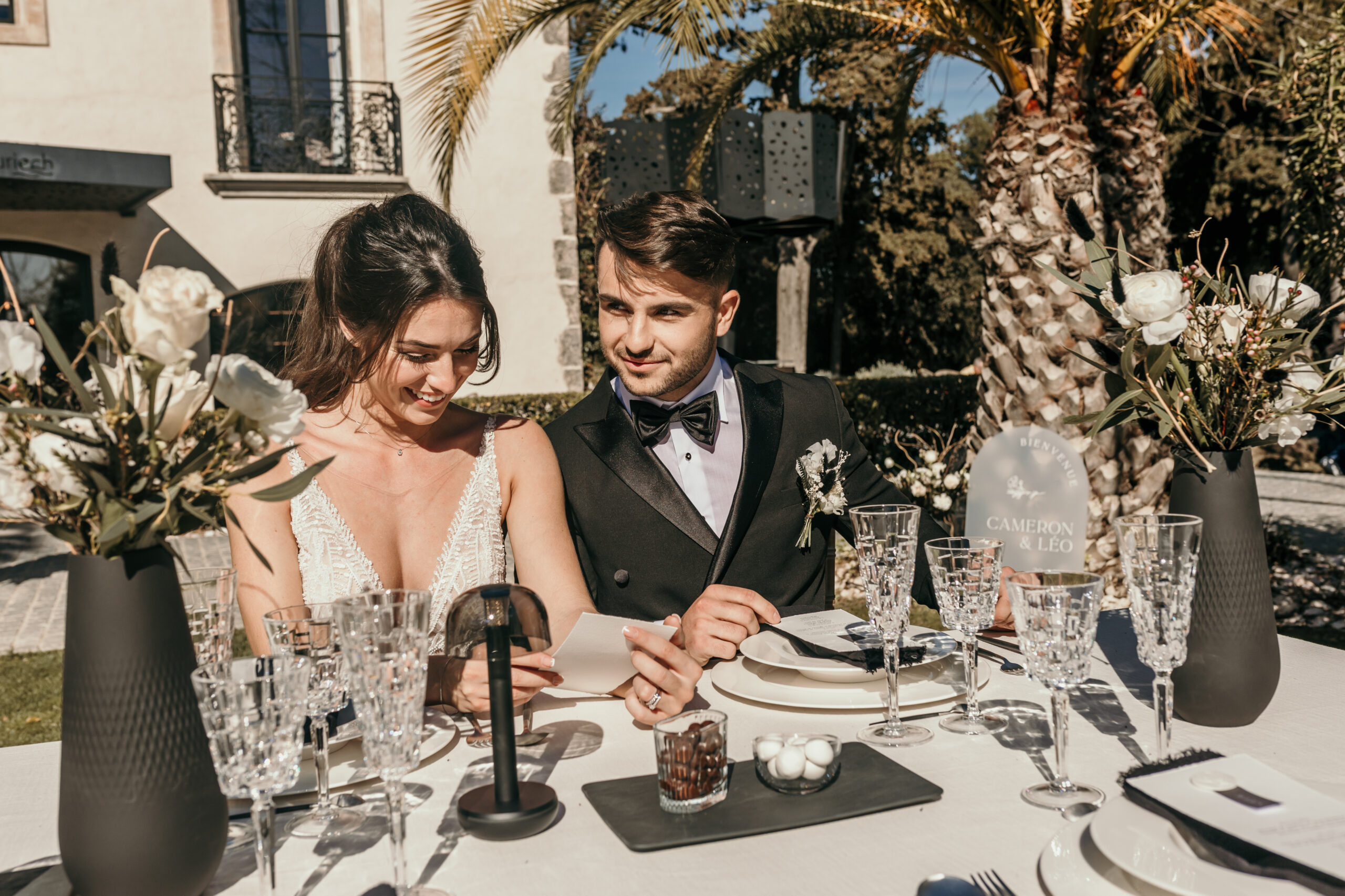 couple de mariés, table mariés, mariage élégant et chic Montpellier, costume de marié noir, robe de mariée décolleté en dentelle, vase noir, assiettes porcelaine fine, art de la table haut de gamme, mariage Montpellier, inspiration mariage Montpellier, domaine Tarbouriech à Marseillan, Miss Languedoc-Roussillon 2022